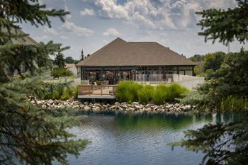 A building with a brown roof is surrounded by water and trees.